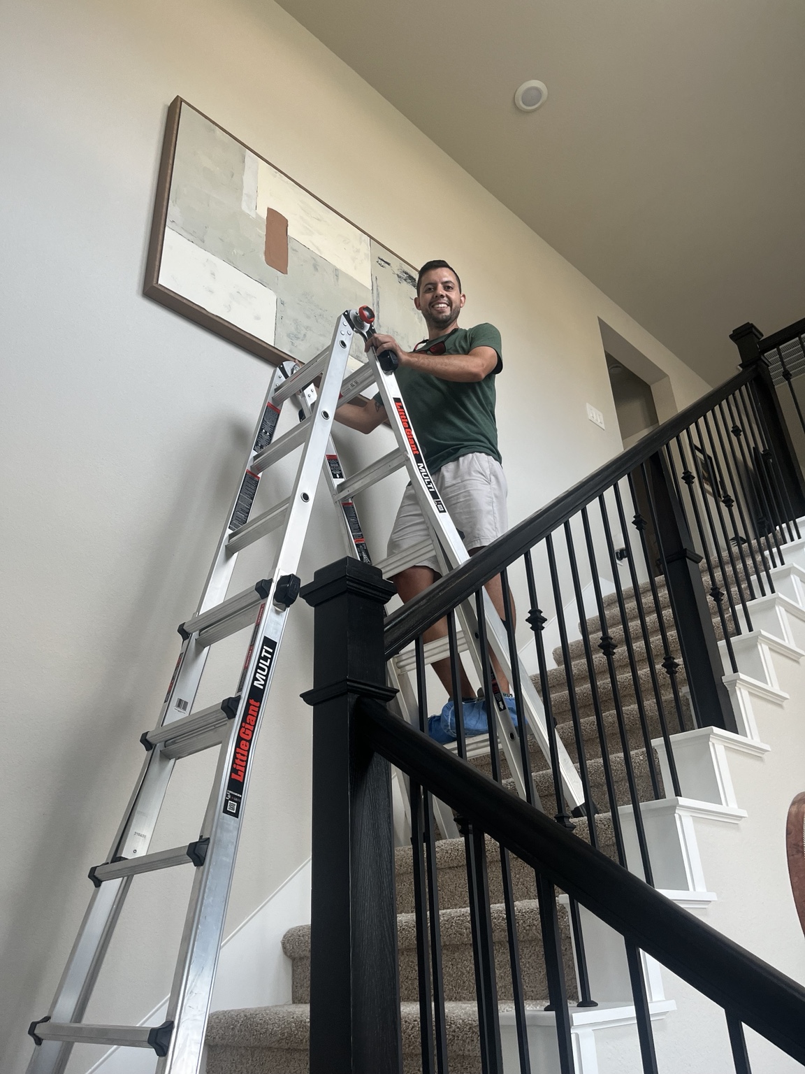 Paul carefully hanging large artwork in a home near The Woodlands and Magnolia, Texas